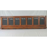 A mahogany framed diary chalkboard featuring the days of the week with double hooks under,