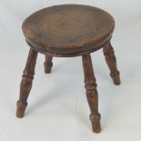 A delightful circular elm topped stool raised over four turned legs, 24cm dia.