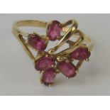 A 9ct gold and pink topaz abstract design ring, six oval cut stones claw set in yellow gold,
