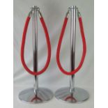 A pair of cinema foyer freestanding chrome crowd posts each with red braided rope and clips.