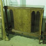 A smart 1930s display cabinet having enhanced walnut central door flanked by twin glazed doors,