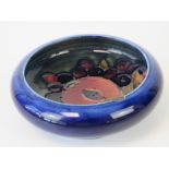 A Moorcroft shallow bowl with inverted rim, pomegranate decoration on a blue ground, 10.