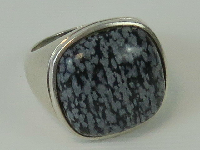 A silver ring having large grey and blac