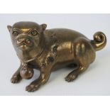 A Chinese brass figurine of a recumbent Pekinese dog with 'bell' collar, 14cm in length.