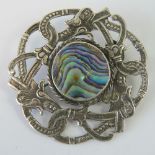 A white metal Celtic brooch featuring three mythical beast heads in a stylised knot and having