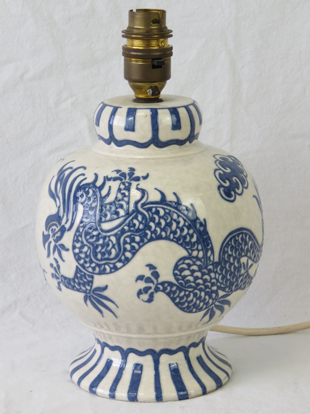 A Charlotte Rhead Bursley Ware lamp having off white ground with blue dragon and clouds upon,
