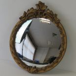 A circular convex hall mirror with gilt frame havign Rococo style crest, 40cm high.