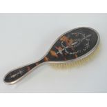 A HM silver hairbrush with tortoiseshell back inlaid with white metal foliate design,