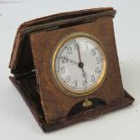 An early 20thC travelling alarm clock with skeleton hands, in folding leather case, case A/F.