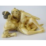 A 19th century carved ivory netsuke in the form of a man and woman in erotic pose,