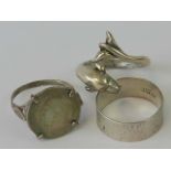 Three silver rings; one in the form of a dolphin, size Q, one with claw set threepence coin, size P,