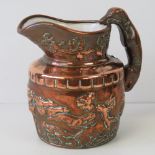 A copper cased Staffordshire pottery jug having greyhound handle and stag hunting scene in relief,