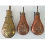 Two 19th century copper and brass shot flasks embossed with cannons, arms and flags.