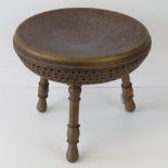 A low Indian stool having engraved copper seat with pierced decoration to sides,