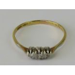 A vintage 18ct gold and diamond ring having three graduated round cut stones set in white metal on