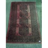 A red ground Middle Eastern rug having four central medallions, approx 100 x 170cm.