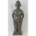 A cast iron patinated flatback fireside figure of a Dutch boy with hands in pockets.