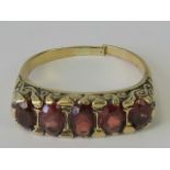 A Victorian ring having five oval cut garnets in scrolling carved head, hallmarks worn, band cut, 4.