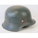 A reproduction WWII German army helmet having camouflage paint, liner and chin strap.