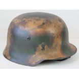 A fine reproduction WWII German Infantry helmet having camouflage paint, liner and chin strap.