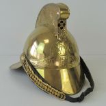 A reproduction brass fireman's helmet having black fabric liner and fish scale chin strap.