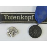 A WWII German SS group; metal Totenkopf cap badge, Totenkopf cuff title,
