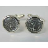 A pair of cufflinks in the form of a speedometer and fuel gauge.