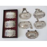 A set of five silver plated decanter labels having vine and foliate borders being; Whisky, Rum,