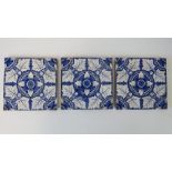 A set of three blue and white ceramic tiles having foliate design upon, each measuring 15.3cm sq.