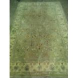 A contemporary green ground woolen rug having cream border and floral decoration throughout,