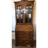 A walnut veneer bureau bookcase, twin glazed doors and shelves within over the base with fall front,