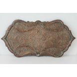 A 19thC Indian relief work copper tray of shaped rectangular form with pierced scroll borders and