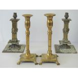 A pair of early 20th century plain turned brass candlesticks each raised over a square shaped base,