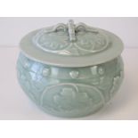 A contemporary celadon green Oriental pot complete with lid having relief foliate pattern,