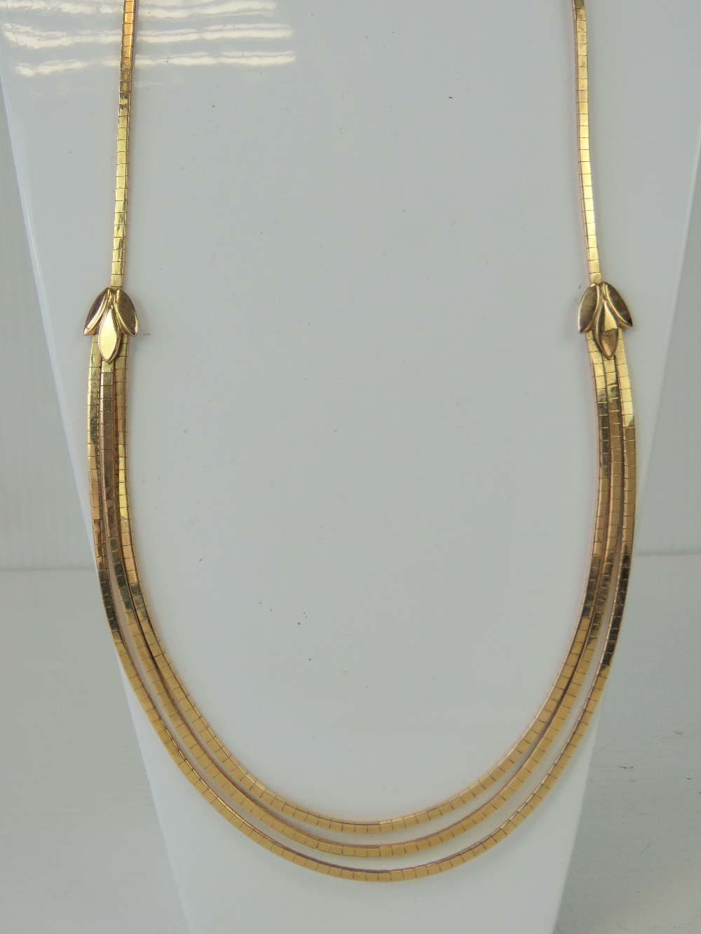 An 18ct gold articulated necklace having central trio of graduated snake link chain with triform