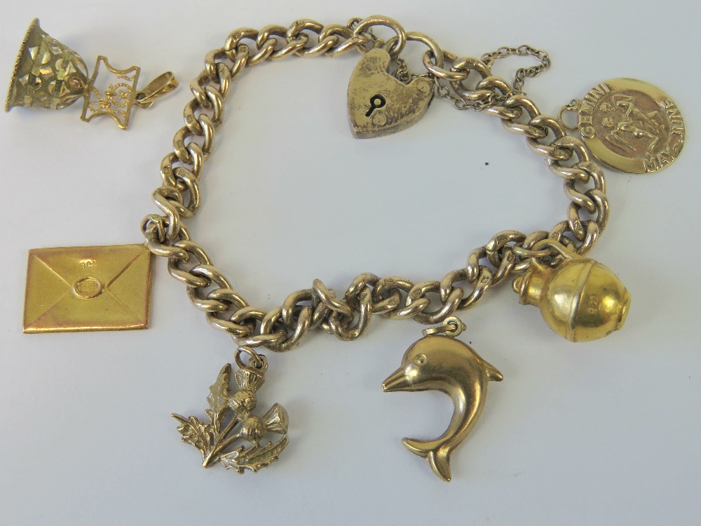 A gilded HM silver curb link charm bracelet having two attached 9ct gold charms,