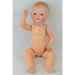 An Armand Marsaille bisque headed doll with composite body and jointed limbs, eyes a/f,