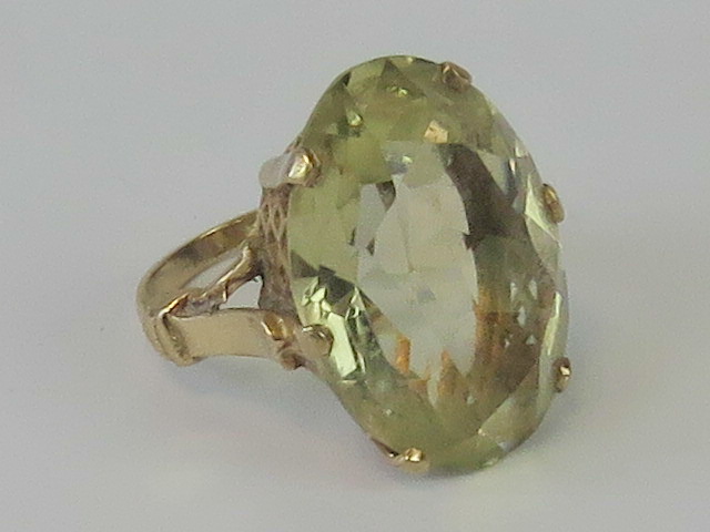 A citrine cocktail ring, oval faceted stone approx 2.5 x 1.8cm, claw set in yellow metal, size M-N.