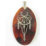 A delightful Edwardian tortoiseshell pendant having white metal inlaid swag design and white metal