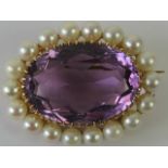 An Amethyst and pearl brooch having large central oval faceted claw set amethyst, approx 2.1 x 1.