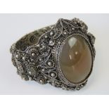 A highly detailed white metal filigree cuff bangle having large oval chalcedony cabachon to front,