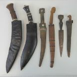 Two kukris with scabbards, three daggers with sheaths and another without sheath. Six items.
