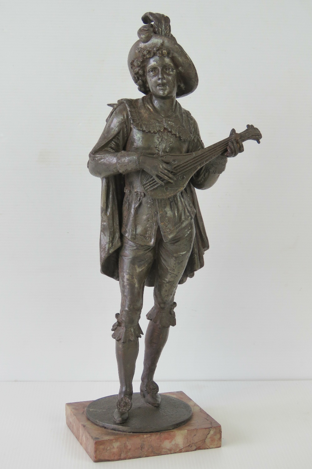 A late 19th century speltre figure of a minstrel with lute in standing pose upon a rouge marble