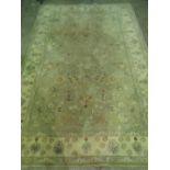 A contemporary green ground woollen rug having cream border and floral decoration throughout,