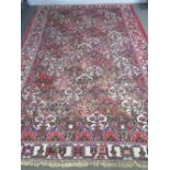A 20thC Middle Eastern bordered carpet with a multi-coloured lozenge panelled centre ground,