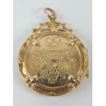A Victorian 9ct gold locket of circular form having engraved bow with floral swag to front and