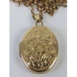 A yellow metal locket having floral engraving to front,