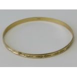 A 9ct yellow gold bangle having engraved pattern throughout, hallmarked 375, 6.8cm dia, 7.2g.