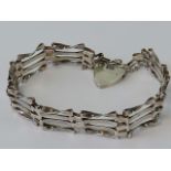 A HM silver gate link bracelet having four bars and complete with HM silver heart padlock clasp,