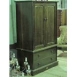 A wardrobe having two doors over two drawers all raised over plinth base,